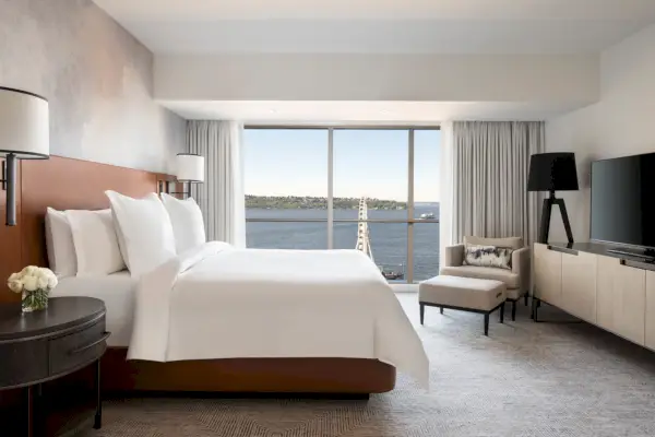 Luksushotellihuone, jossa on valkoinen sänky ja näköala lahdelle