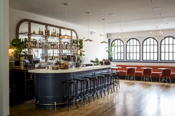 En inomhusbar med trägolv, naturlig belysning och vita väggar.