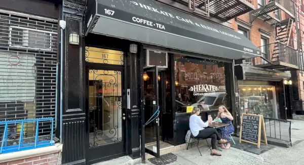 Exteriören av Hekate på en stadsgata med en grön markis och utomhusbord.