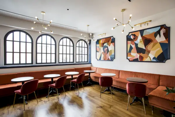 En inomhusbar med trägolv, naturlig belysning och vita väggar.