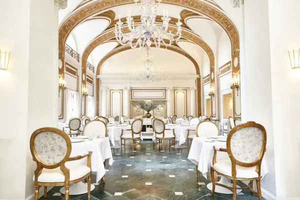 Tyylikkään ravintolan sisustus isoilla riippuvaloilla, ikkunoilla yksityiskohdilla, punaisilla kattauksilla ja himmeällä valaistuksella.