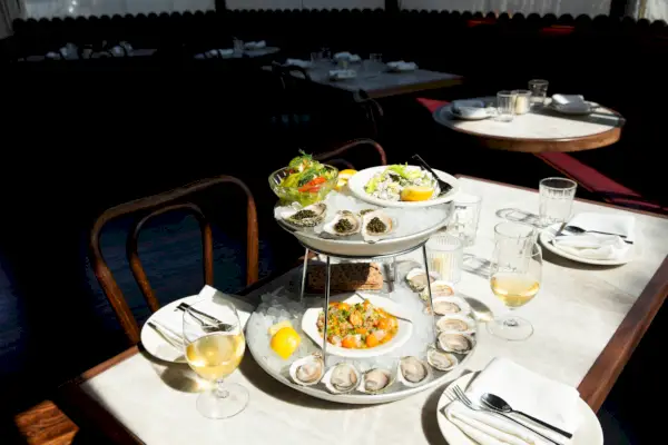 Ravintolan sisätila, jossa yksi pöytä lähellä kameraa, kaksikerroksinen osterilautanen ja sivut sen päällä.