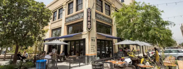 Ravintolan ulkopuoli korttelikulmassa, jossa on ulkopöytiä ja -varjoja sekä kyltti, jossa lukee: Rappahannock Oyster Bar.