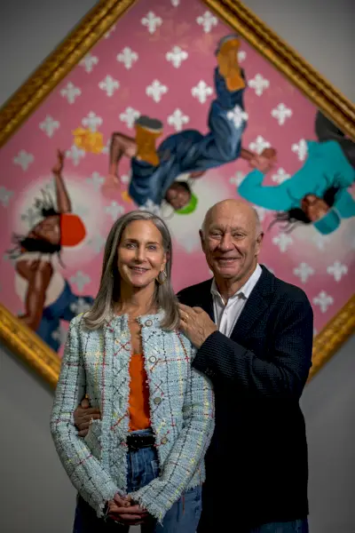 Nainen ja mies poseeraavat vaaleanpunaisen maalauksen edessä