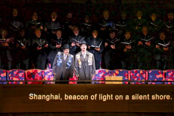 Kaksi laulajaa esiintyy suuren kuoron tukemana