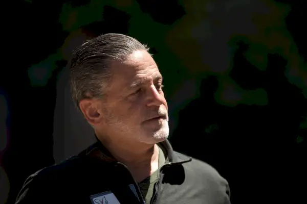 Mies mustassa puserossa tummaa taustaa vasten