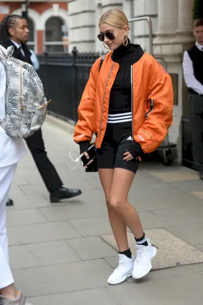 bieber ubrany w czarny komplet z pomarańczową kurtką i białymi tenisówkami