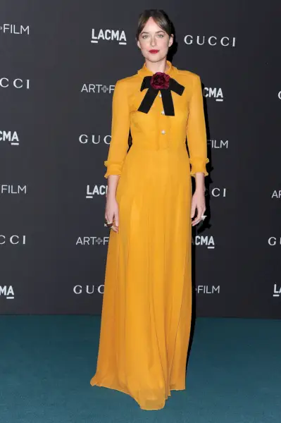 Johnson ubrana w musztardową sukienkę z czarną wstążką.